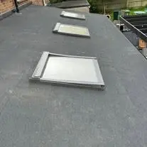 Finished grey flat roof on an extension with three rooflights set into it