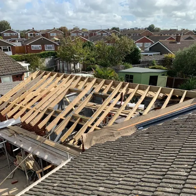 Bungalow roof stripped back to its timbers, seen across a neighbouring tiled roof